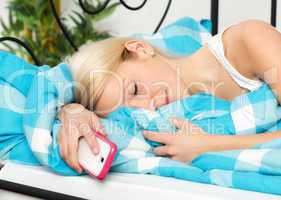 Frau mit Handy im Bett schläft