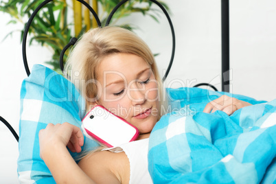 Frau mit Handy im Bett ist eingeschlafen