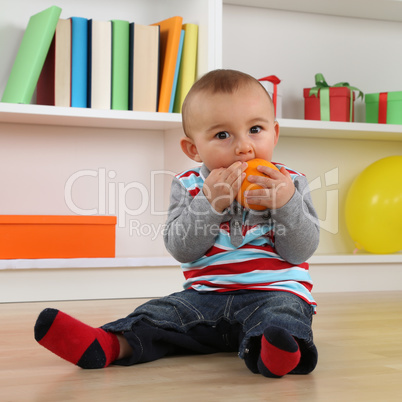 Kleines Baby isst eine Orange Frucht
