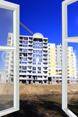 opened window to construction of multistorey house and crane