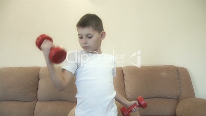 Little boy with dumbbells in his hands.Athletic development, fitness and sports for children concept