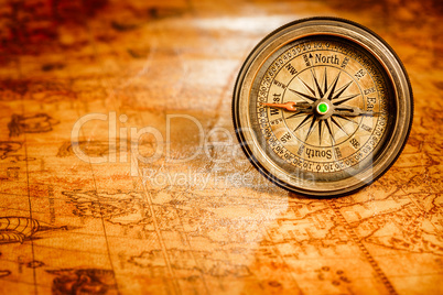 Vintage compass lies on an ancient world map.