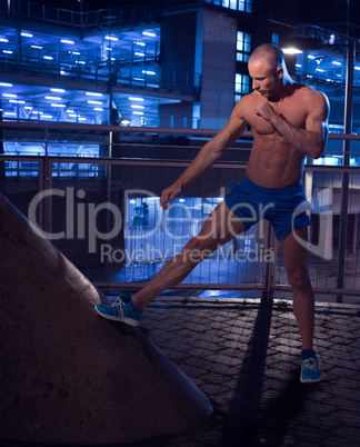 Muscular Man in a Building Stretching his Leg