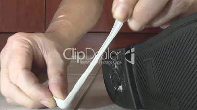 man removes chewing gum from the sole of his shoe