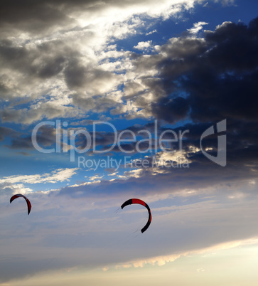 Two silhouette of power kites at sunset sky