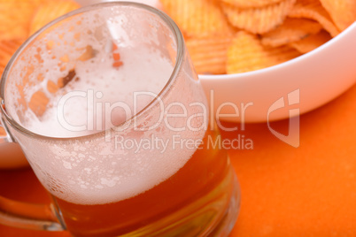 Glass of light beer and potato chips on a wooden table