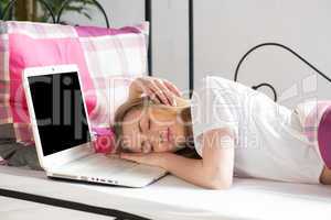Blonde Frau schläft im Bett am Laptop ein