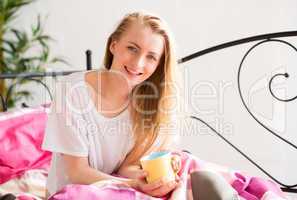 Blonde Frau mit Kaffee im Bett