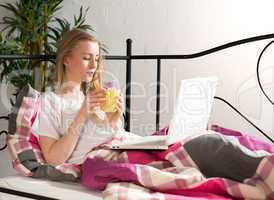 Frau mit Laptop im Bett trinkt Kaffee