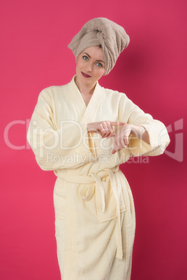 Frau im Bademantel cremt sich die Hände ein