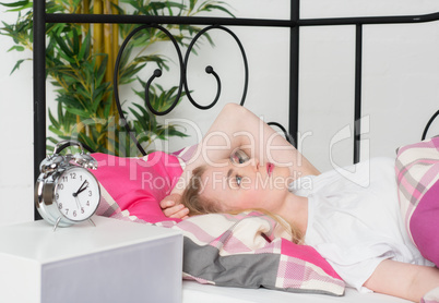 Blonde Frau liegt mit Schlafproblemen im Bett