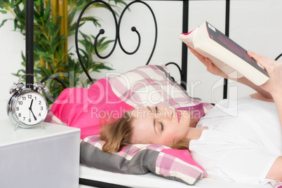 Blonde Frau liest im Bett ein Buch