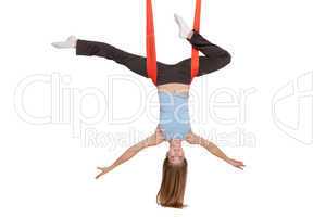 Young woman doing anti-gravity aerial yoga in hammock on a seamless white background.