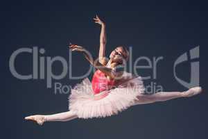 Beautiful female ballet dancer on a grey background. Ballerina is wearing  pink tutu and pointe shoes.