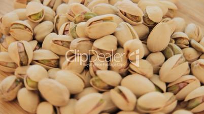 Roasted pistachios rotate on wood plate