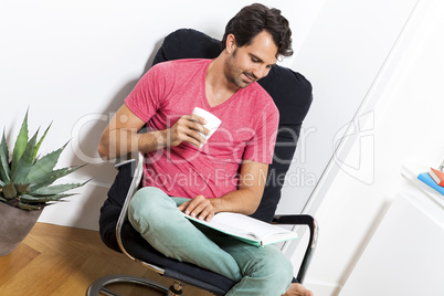 Man Sitting on Chair with Book and a Drink