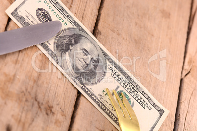 american money on wooden plate with knife and fok
