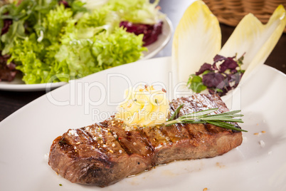 Grilled beef steak topped with butter and rosemary