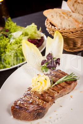 Grilled beef steak topped with butter and rosemary