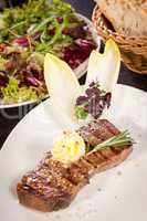 Grilled beef steak topped with butter and rosemary