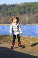 young girl goes in roller skates on the ground