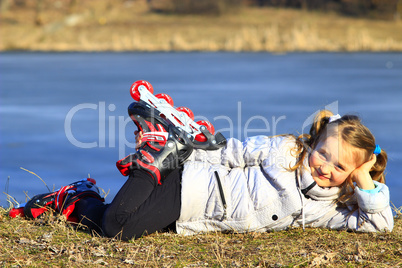 young girl in roller skates lays on the ground