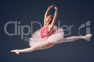 Beautiful female ballet dancer on a grey background. Ballerina is wearing  pink tutu and pointe shoes.