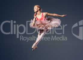 Beautiful female ballet dancer on a grey background. Ballerina is wearing  pink tutu and pointe shoes.