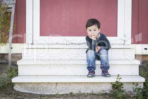 Cute Mixed Race Boy Sitting on the Steps of a Barn