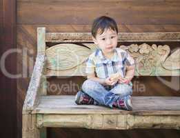 Cute Mixed Race Boy Sitting on Bench Eating Sandwich