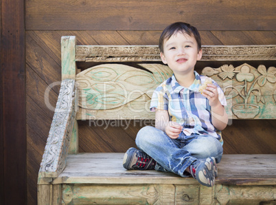 Cute Mixed Race Boy Sitting on Bench Eating Sandwich