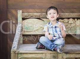 Cute Mixed Race Boy Sitting on Bench Eating Sandwich