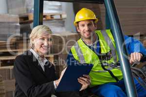 Forklift driver and manager smiling at camera