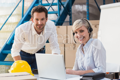 Warehouse managers using laptop and wearing headset