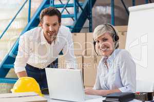 Warehouse managers using laptop and wearing headset