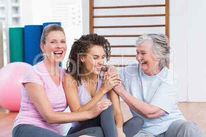 Playful female friends sitting in gym