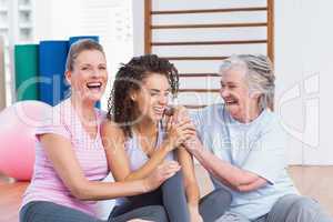 Playful female friends sitting in gym