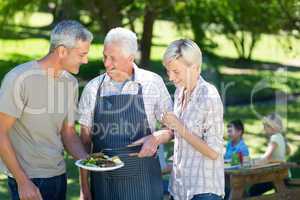 Happy couple with grandfather doing barbecue