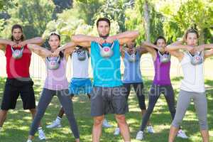 Fitness group working out in park with kettle bells