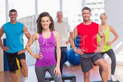 Instructor with fitness class performing step aerobics exercise