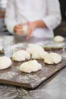 Baker kneading uncooked dough on worktop