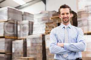 Smiling manager with arms crossed in warehouse