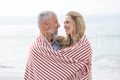Happy couple smiling at each other with blanket around them