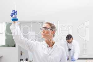 Scientist examining blue precipitate in baker