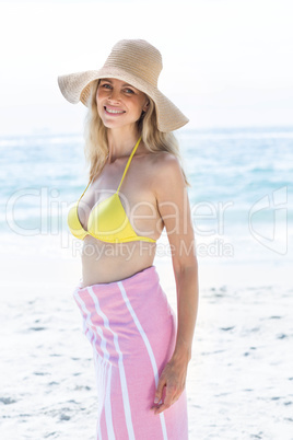 Smiling blonde standing by the sea and looking at camera