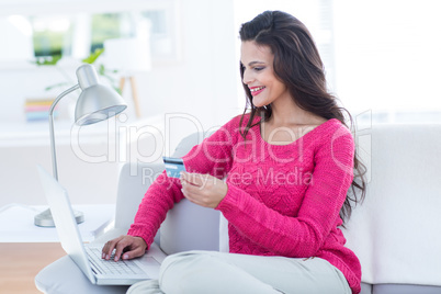 Smiling beautiful brunette doing online shopping on the couch