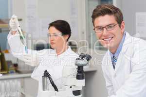 Scientists working with microscope and test tube