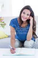 Smiling beautiful brunette writing in diary