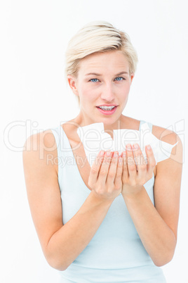 Sick woman holding tissues looking at camera