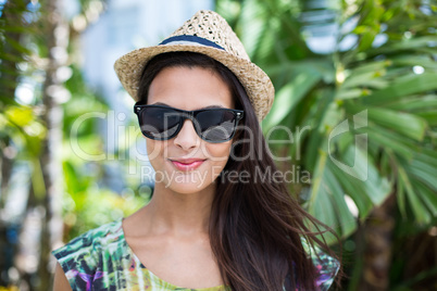 Smiling beautiful brunette wearing straw hat and sun glasses
